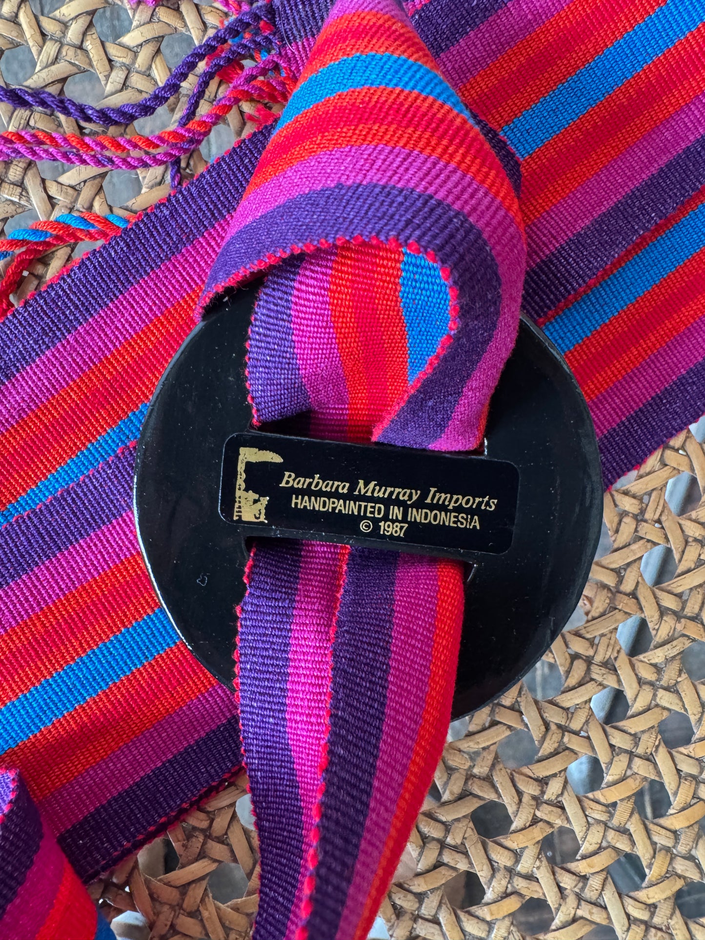 Colorful woven belt with a black label on a textured surface