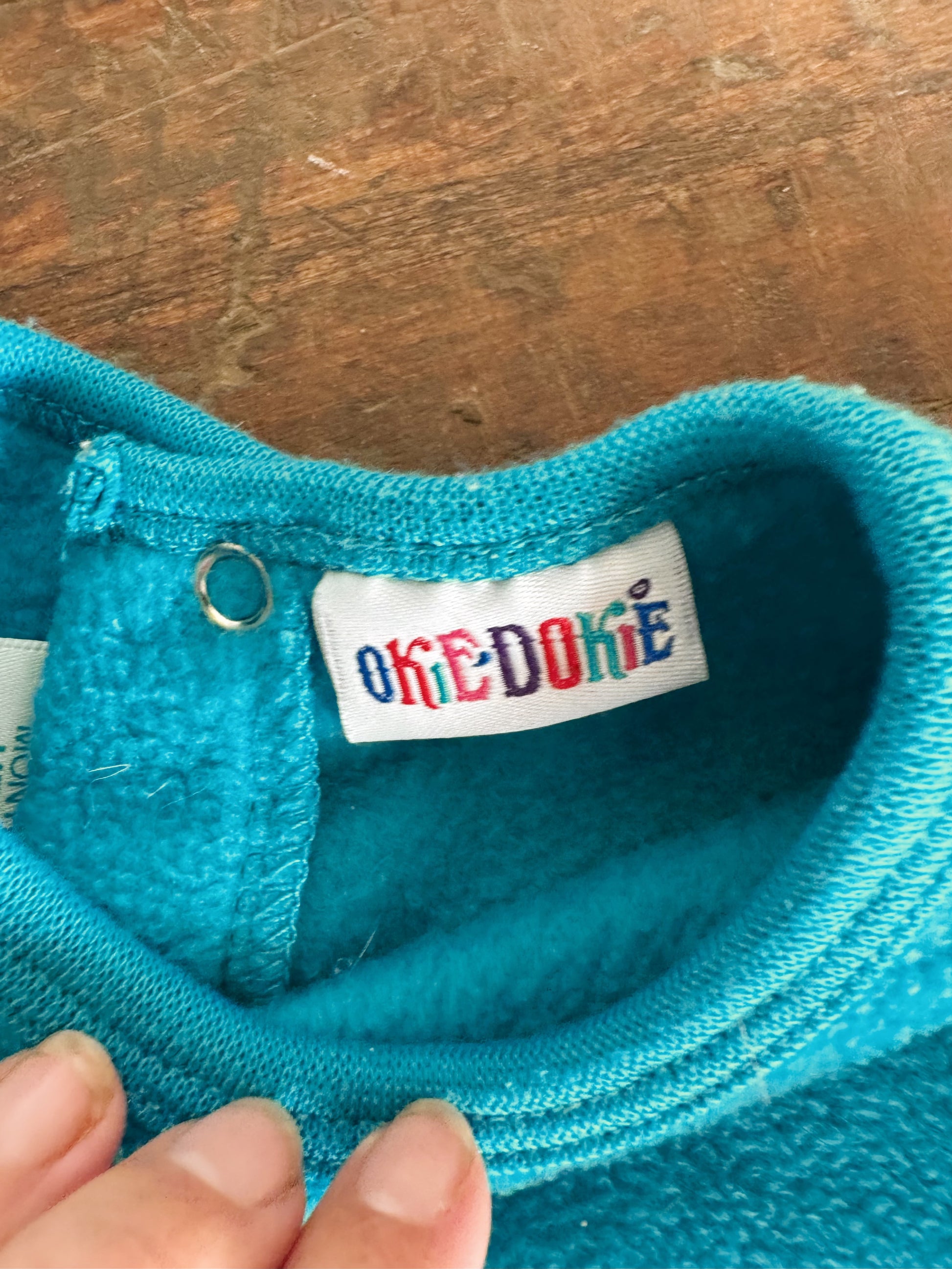 Close-up of a blue fabric with an 'Oke-Dokie' label on a wooden surface