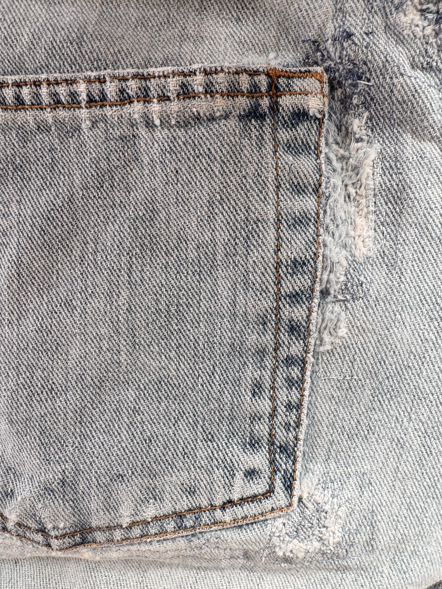 Close-up of a distressed denim fabric with frayed edges.