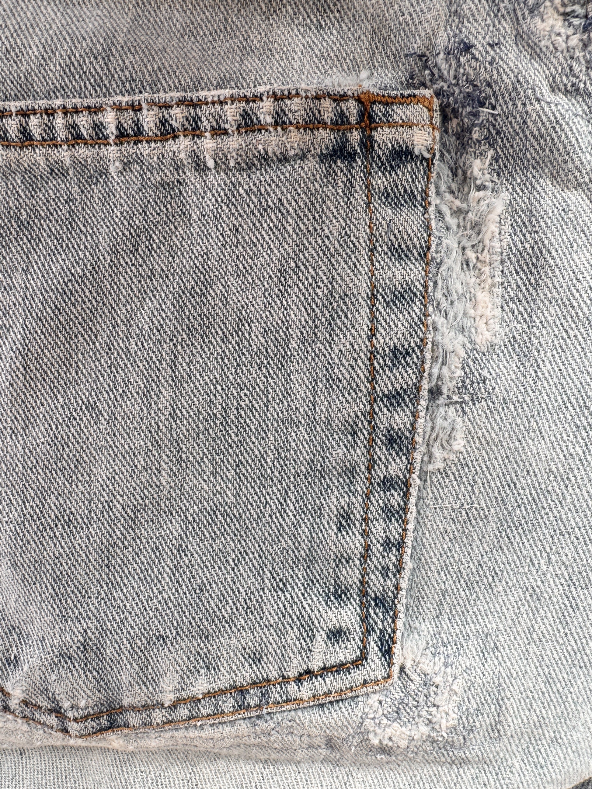 Close-up of a distressed denim fabric with frayed edges.
