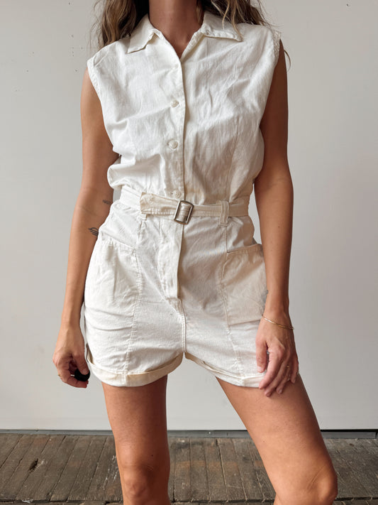 Person wearing a white sleeveless romper against a plain background