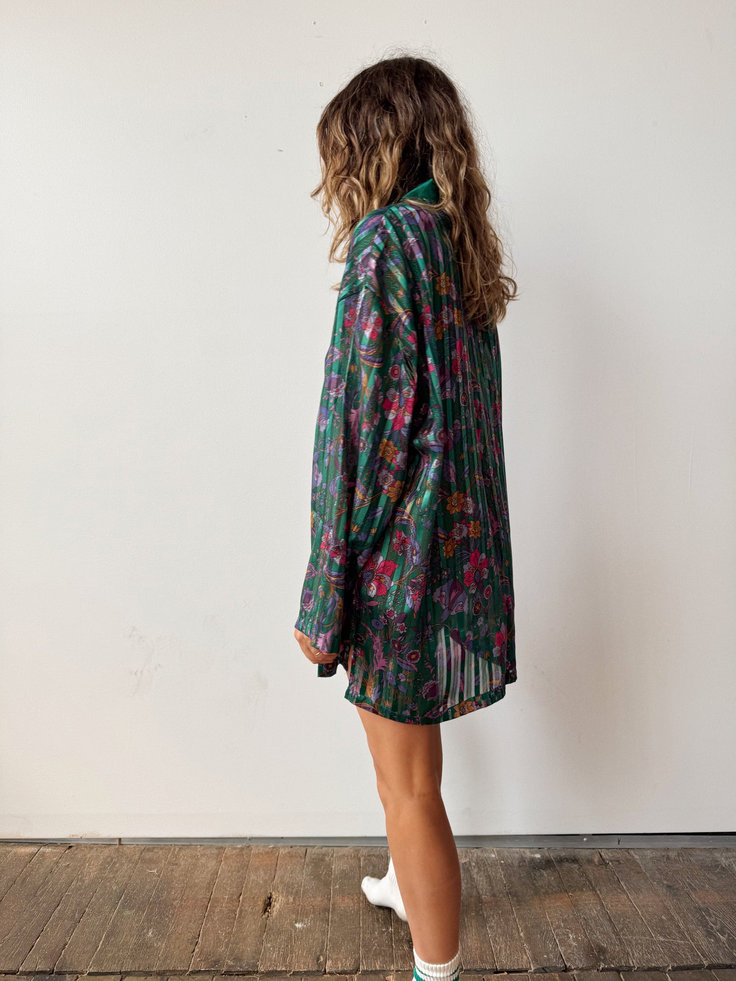 Person wearing a floral dress standing against a white wall.