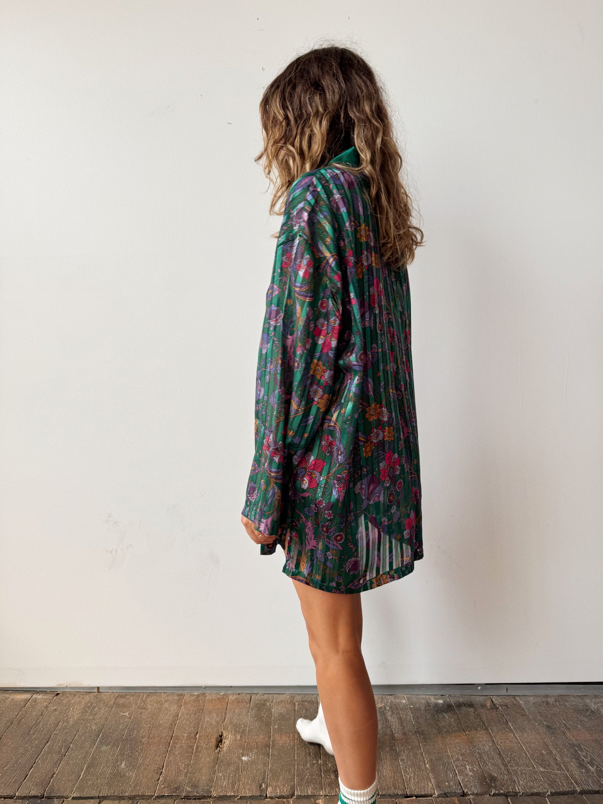 Person wearing a floral dress standing against a white wall.